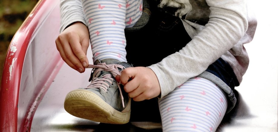 Ein Kind bindet sich die Schuhe auf einer Rutsche